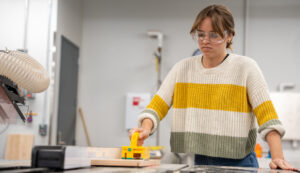 Image of student pushing wood through the table saw.