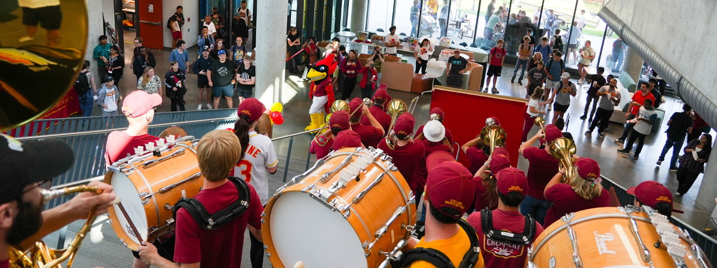 Iowa State Marching Band playing on the Stepatorium of the Student Innovation Center to a crowd of Iowa State students and Cy the mascot.