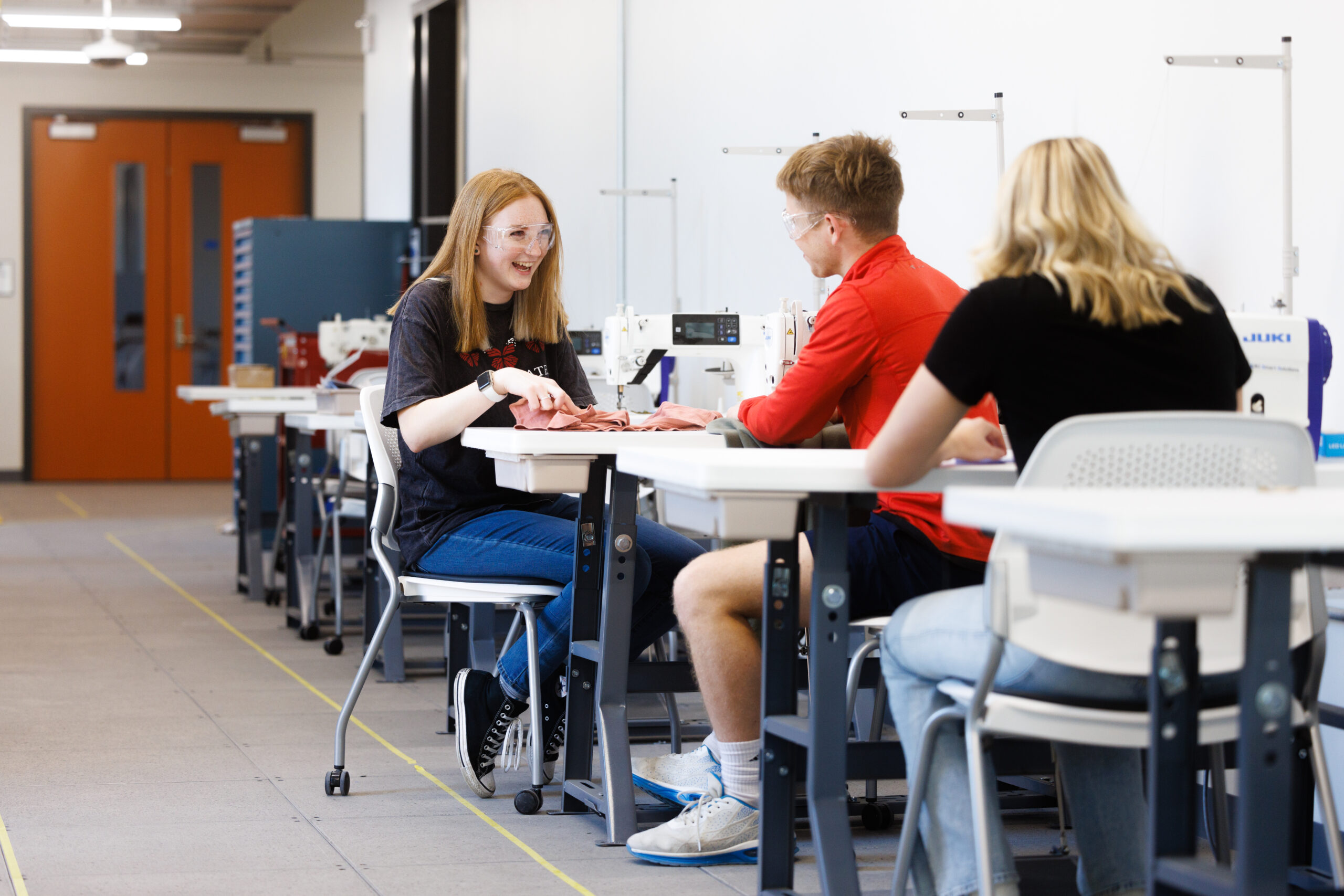 Image of students in the makerspace sewing their extracurricular projects together, smiling and laughing.